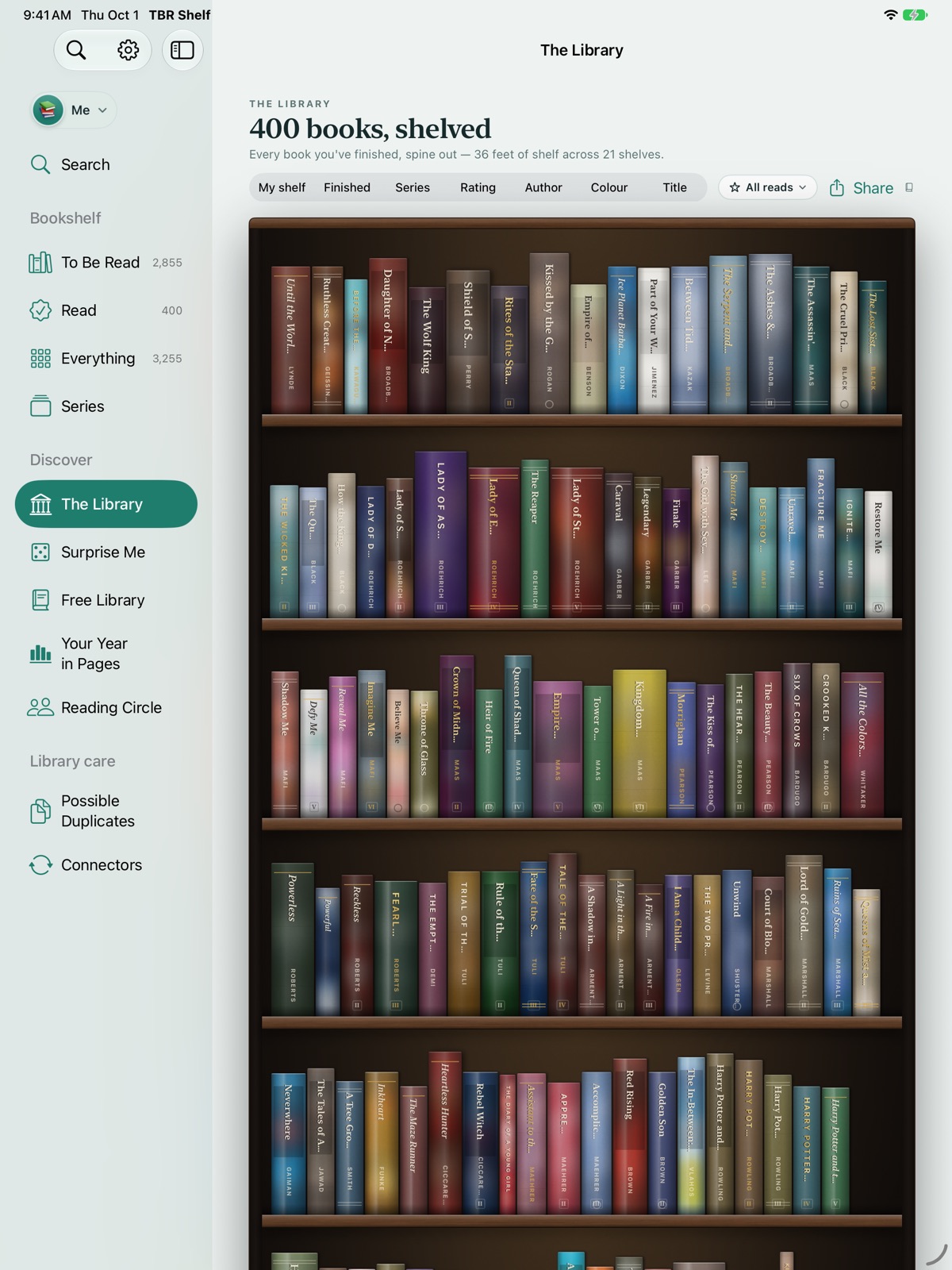 The Library on iPad: rows of colourful book spines on walnut shelves, with a sidebar of shelves and tools